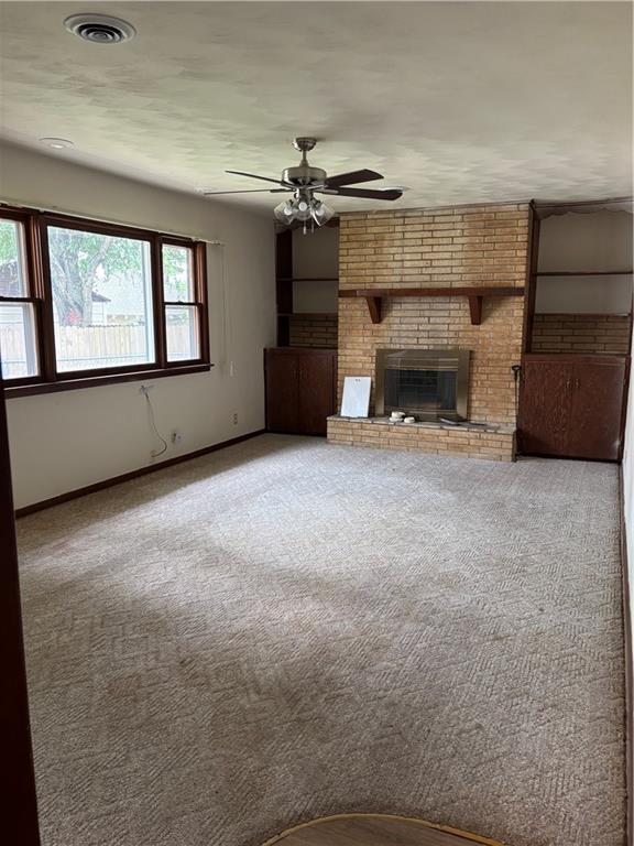 420 S Walnut St, Iola, KS 66749 - unfurnished living room with a ceiling fan, a brick fireplace, and carpet floors
