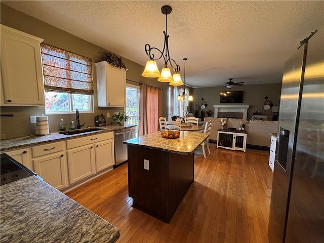 1840 W Fredrickson Cir, Olathe, KS 66061 - kitchen featuring appliances with stainless steel finishes, a textured ceiling, open floor plan, a kitchen island, and a fireplace
