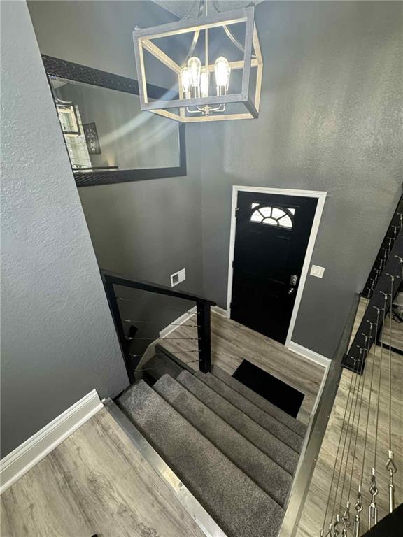 213 SW Palo Dr, Blue Springs, MO 64014 - staircase featuring wood finished floors and a chandelier