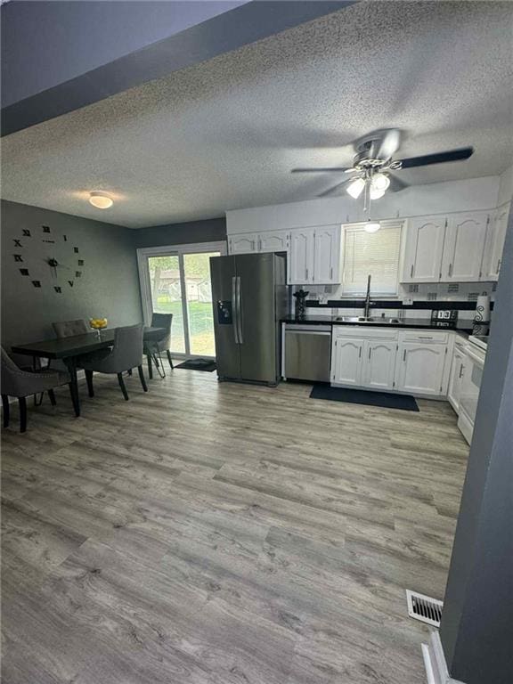 213 SW Palo Dr, Blue Springs, MO 64014 - kitchen with black fridge with ice dispenser, stainless steel dishwasher, white cabinets, a textured ceiling, and dark countertops
