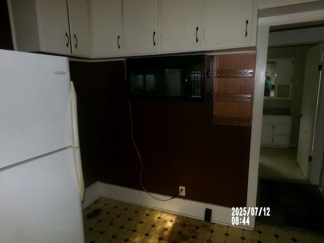 211 W Madison St, Yates Center, KS 66783 - kitchen with freestanding refrigerator, black microwave, white cabinetry, and tile patterned floors