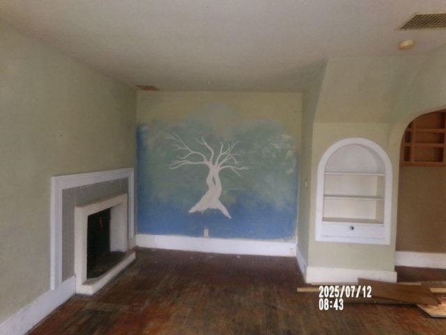 211 W Madison St, Yates Center, KS 66783 - unfurnished living room featuring wood finished floors, built in shelves, and a fireplace