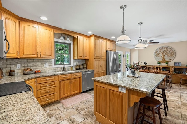 1306 Ruby St, Carrollton, MO 64633 - kitchen featuring backsplash, a kitchen bar, a ceiling fan, a center island, and stainless steel appliances