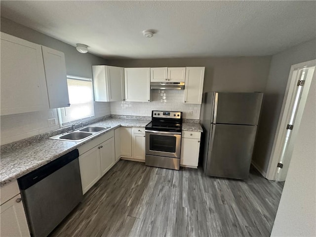 6146 Parkview Ave, Kansas City, KS 66104 - kitchen with appliances with stainless steel finishes, under cabinet range hood, white cabinetry, tasteful backsplash, and a textured ceiling