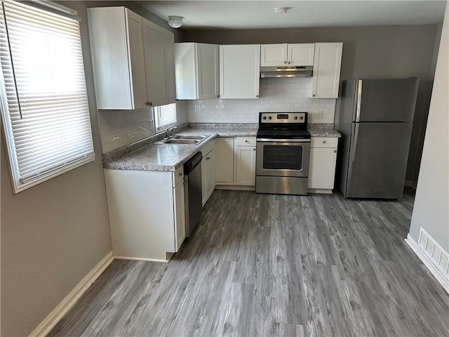 6146 Parkview Ave, Kansas City, KS 66104 - kitchen with appliances with stainless steel finishes, under cabinet range hood, wood finished floors, and decorative backsplash