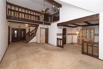 7908 E 96th St, Kansas City, MO 64134 - unfurnished living room with beam ceiling, stairway, a ceiling fan, a high ceiling, and carpet