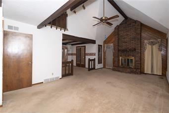 7908 E 96th St, Kansas City, MO 64134 - unfurnished living room featuring carpet flooring, a ceiling fan, and a fireplace