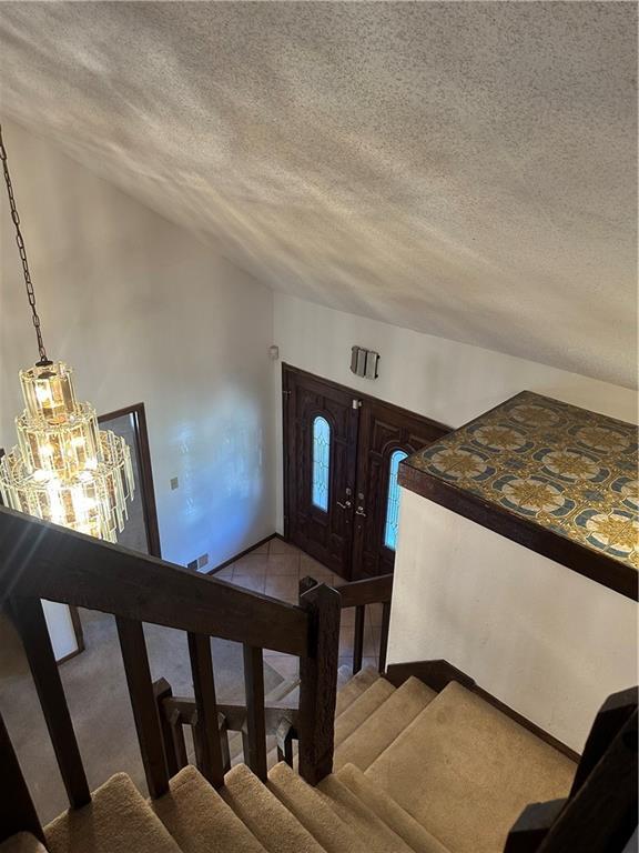 7908 E 96th St, Kansas City, MO 64134 - stairway with a textured ceiling, a chandelier, and vaulted ceiling