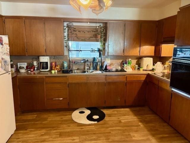 2302 Crawford Ave, Parsons, KS 67357 - kitchen with black appliances, light wood finished floors, light countertops, and brown cabinetry