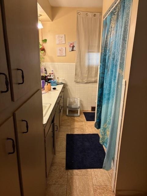 2302 Crawford Ave, Parsons, KS 67357 - bathroom with tile patterned flooring, a shower with curtain, a wainscoted wall, tile walls, and vanity