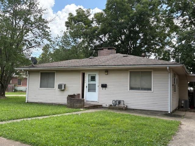 2302 Crawford Ave, Parsons, KS 67357 - view of front of home with a front yard, an AC wall unit, and a chimney