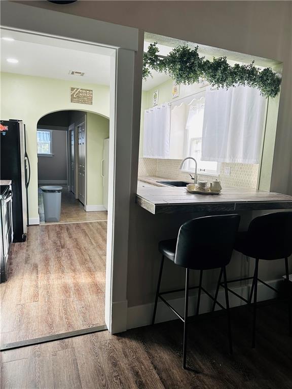507 E Jefferson St, Pittsburg, KS 66762 - kitchen featuring arched walkways, wood finished floors, freestanding refrigerator, and decorative backsplash
