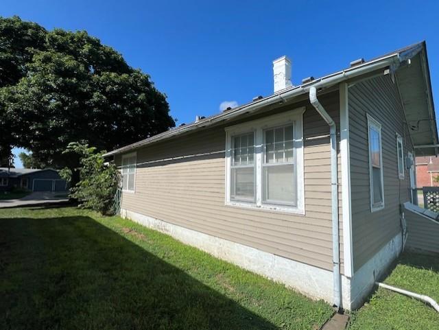 1110 W Main St, Chanute, KS 66720 - view of property exterior featuring a chimney and a lawn