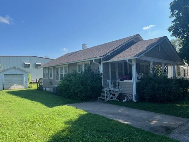 1110 W Main St, Chanute, KS 66720 - view of front of property with a front lawn, an outdoor structure, a chimney, and a shingled roof