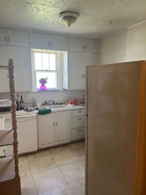 1110 W Main St, Chanute, KS 66720 - kitchen featuring freestanding refrigerator, white dishwasher, light countertops, white cabinets, and light tile patterned floors