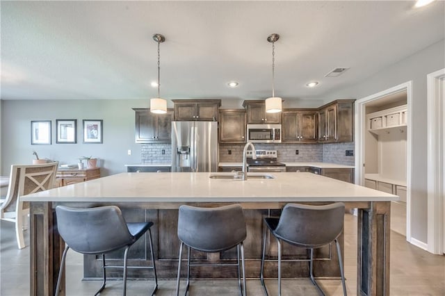 4246 Lakeview Ter, Basehor, KS 66007 - kitchen featuring appliances with stainless steel finishes, light countertops, tasteful backsplash, a center island with sink, and dark brown cabinets