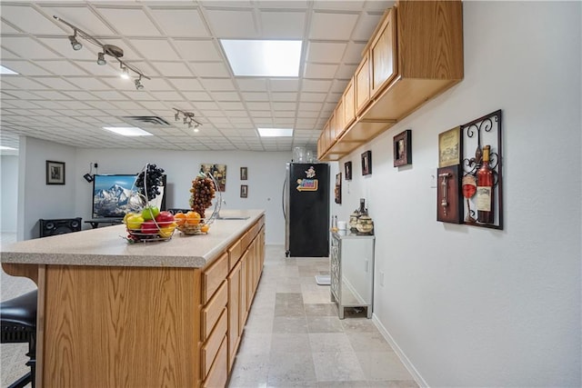 1702 Cedar Ridge Rd, Parsons, KS 67357 - kitchen with a drop ceiling, freestanding refrigerator, light countertops, a kitchen bar, and a kitchen island with sink