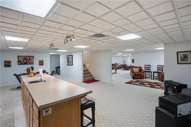 1702 Cedar Ridge Rd, Parsons, KS 67357 - kitchen featuring a breakfast bar, light carpet, open floor plan, a kitchen island with sink, and a paneled ceiling