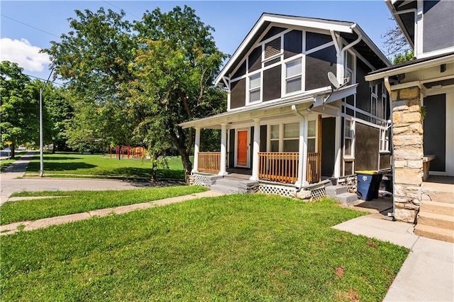 4001 Tracy Ave, Kansas City, MO 64110 - view of front of home with a porch, a front yard, stone siding, and a playground