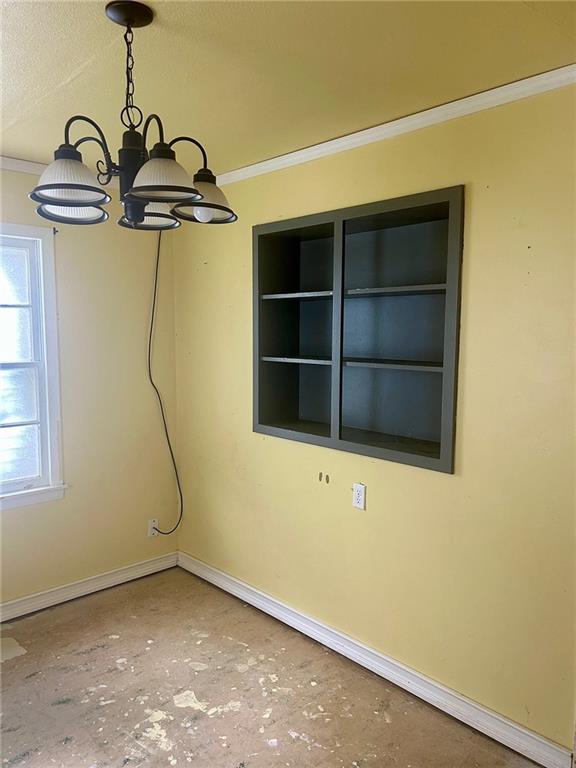 3107 Wood Ave, Parsons, KS 67357 - spare room featuring crown molding and a chandelier