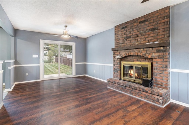 2005 Manor Pl, Blue Springs, MO 64015 - unfurnished living room with ceiling fan, a brick fireplace, wood finished floors, wainscoting, and a textured ceiling