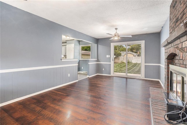 2005 Manor Pl, Blue Springs, MO 64015 - unfurnished living room featuring wood finished floors, a ceiling fan, a textured ceiling, a fireplace, and a wainscoted wall