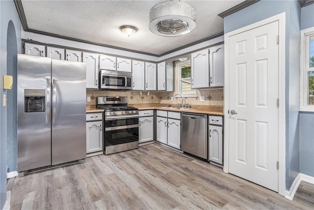 2005 Manor Pl, Blue Springs, MO 64015 - kitchen with stainless steel appliances, light wood-style flooring, backsplash, a textured ceiling, and light countertops