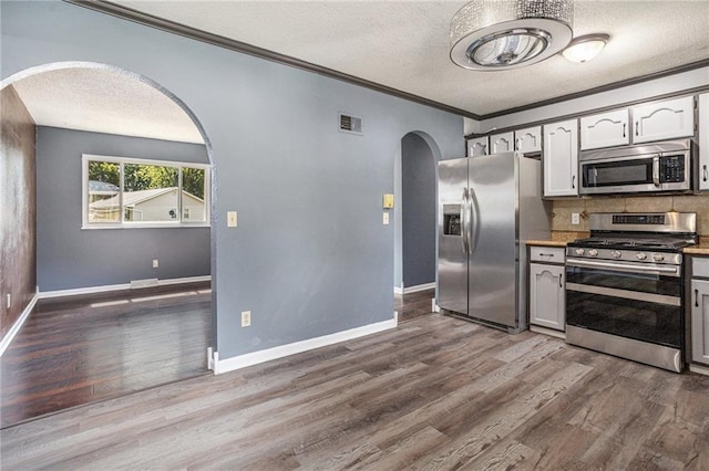 2005 Manor Pl, Blue Springs, MO 64015 - kitchen with appliances with stainless steel finishes, arched walkways, a textured ceiling, crown molding, and wood finished floors