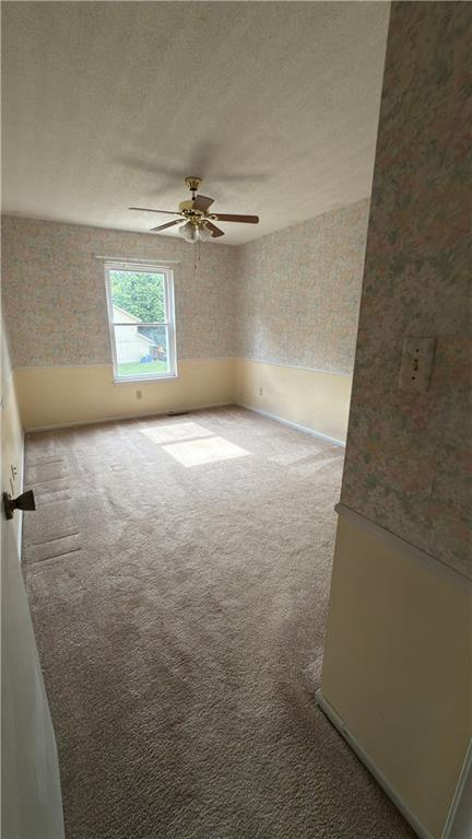 11965 W 66th St, Shawnee, KS 66216 - carpeted empty room featuring wallpapered walls, a ceiling fan, and a textured ceiling
