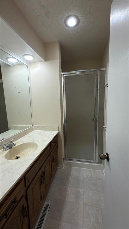 11965 W 66th St, Shawnee, KS 66216 - bathroom with vanity, a shower stall, and a textured ceiling
