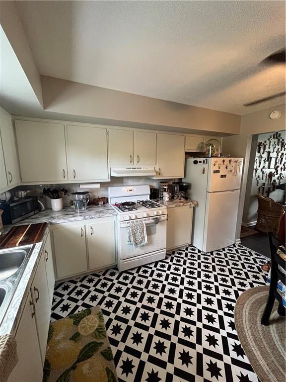 1835-1837 N 77th St, Kansas City, KS 66112 - kitchen featuring white appliances, under cabinet range hood, a textured ceiling, light floors, and light countertops