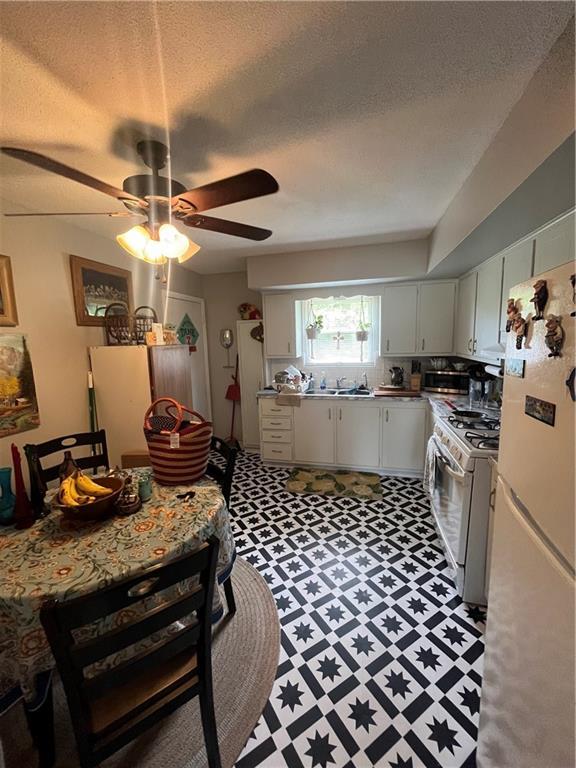 1835-1837 N 77th St, Kansas City, KS 66112 - kitchen with white appliances, a ceiling fan, light floors, a textured ceiling, and white cabinets