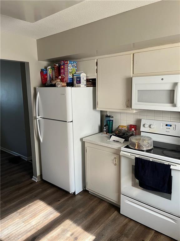1835-1837 N 77th St, Kansas City, KS 66112 - kitchen with white appliances, dark wood finished floors, light countertops, and white cabinetry