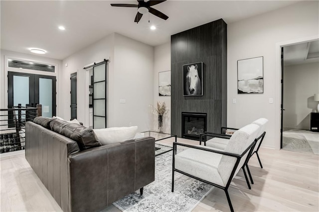 18221 W 168th Ter, Olathe, KS 66062 - living room featuring light wood-style flooring, ceiling fan, a large fireplace, recessed lighting, and a barn door