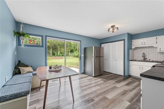 1520 E 18th St, Lawrence, KS 66044 - kitchen with freestanding refrigerator, white cabinets, decorative backsplash, and light wood-type flooring