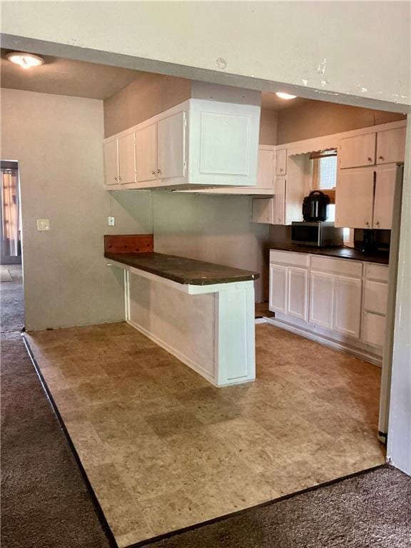308 S 16th St, Independence, KS 67301 - kitchen with dark countertops, white cabinets, and stainless steel microwave