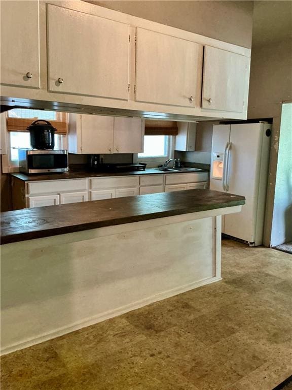 308 S 16th St, Independence, KS 67301 - kitchen with white fridge with ice dispenser, stainless steel microwave, white cabinets, wooden counters, and light floors