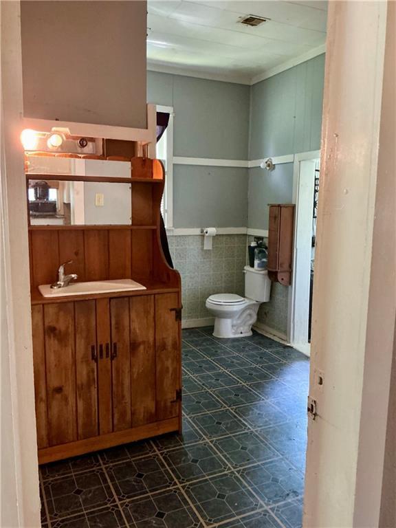 308 S 16th St, Independence, KS 67301 - half bathroom featuring vanity, wainscoting, tile patterned floors, and tile walls