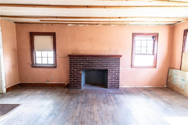 615 Mill St, Neodesha, KS 66757 - unfurnished living room featuring hardwood / wood-style flooring, plenty of natural light, and a brick fireplace