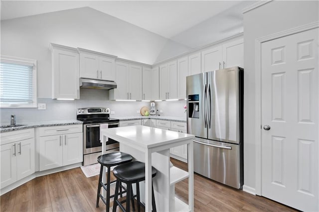 16113 S Cole St, Olathe, KS 66062 - kitchen featuring stainless steel appliances, vaulted ceiling, wood finished floors, a breakfast bar, and white cabinetry