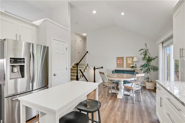 16113 S Cole St, Olathe, KS 66062 - kitchen featuring stainless steel refrigerator with ice dispenser, vaulted ceiling, white cabinetry, light wood finished floors, and a kitchen breakfast bar