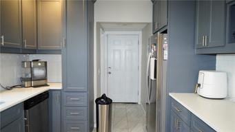 5007 Euclid Ave, Kansas City, MO 64130 - kitchen featuring freestanding refrigerator, stainless steel dishwasher, light countertops, and tile patterned floors