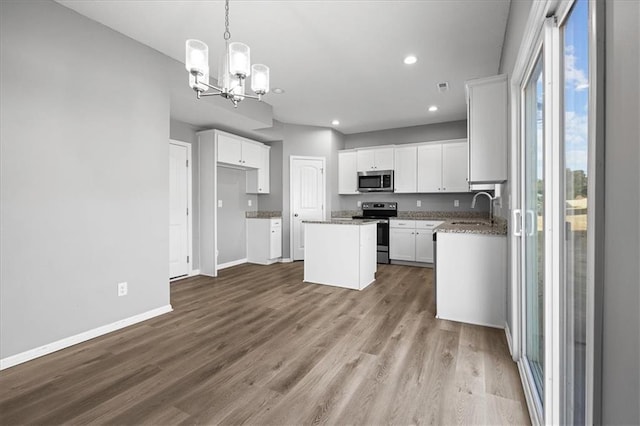 2814 N 100th St, Kansas City, KS 66109 - kitchen with a chandelier, a center island, appliances with stainless steel finishes, wood finished floors, and white cabinetry