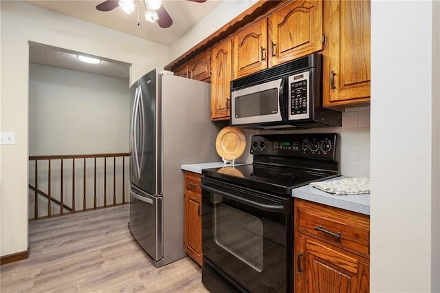 2618 Manor Ter, Lawrence, KS 66046 - kitchen with black range with electric cooktop, brown cabinetry, a ceiling fan, light wood finished floors, and backsplash