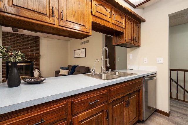 2618 Manor Ter, Lawrence, KS 66046 - kitchen with light wood finished floors, light countertops, dishwasher, and a brick fireplace