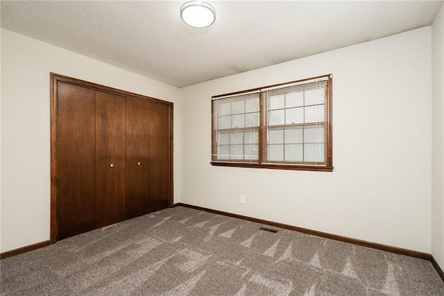 2618 Manor Ter, Lawrence, KS 66046 - unfurnished bedroom featuring dark carpet, a closet, and a textured ceiling