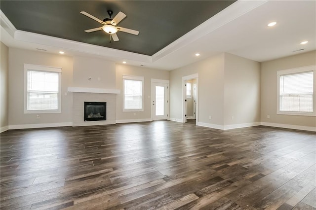 15904 E Cogan Ln, Independence, MO 64050 - unfurnished living room featuring a raised ceiling, ceiling fan, dark wood-style flooring, a glass covered fireplace, and recessed lighting
