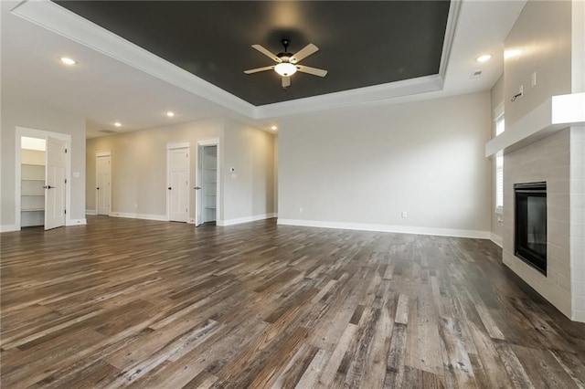 15904 E Cogan Ln, Independence, MO 64050 - unfurnished living room featuring a raised ceiling, ceiling fan, a glass covered fireplace, dark wood-type flooring, and recessed lighting
