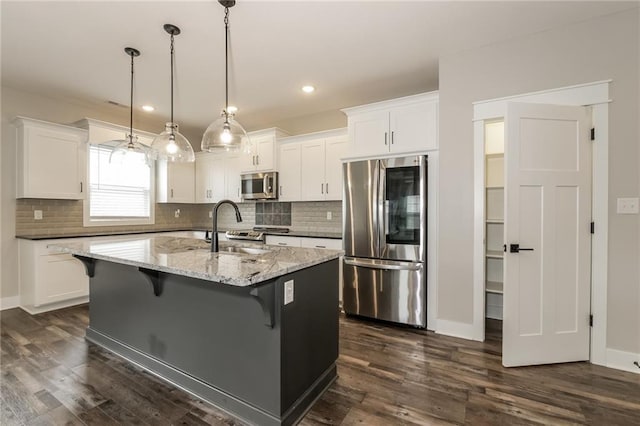 15904 E Cogan Ln, Independence, MO 64050 - kitchen with appliances with stainless steel finishes, white cabinets, tasteful backsplash, a kitchen bar, and dark wood-style floors