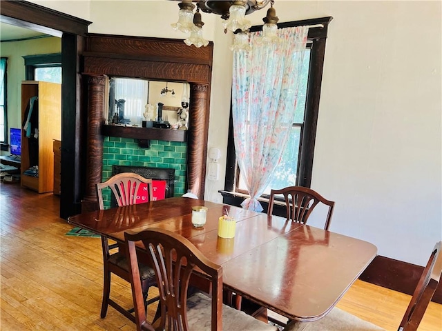 817 S 16th St, Saint Joseph, MO 64501 - dining room featuring light wood-style flooring, healthy amount of natural light, a chandelier, and a brick fireplace